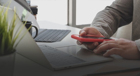 Man using both a laptop and mobile phone