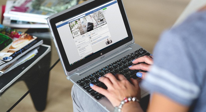 A picture of a man using Facebook, on a laptop 