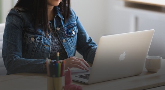 Image of a women using an Apple laptop at a desk 