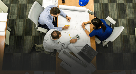 An aerial shot of 3 people sat at a table working collaboratively. 