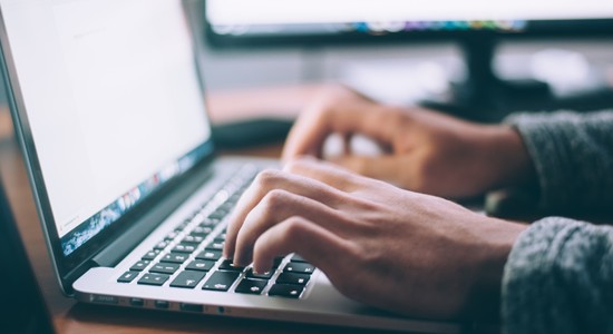 Hands typing on a MacBook computer 