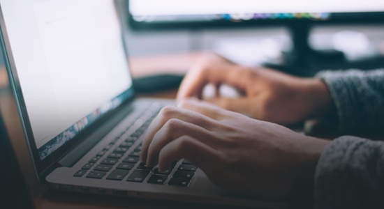 Hands typing on a MacBook computer 