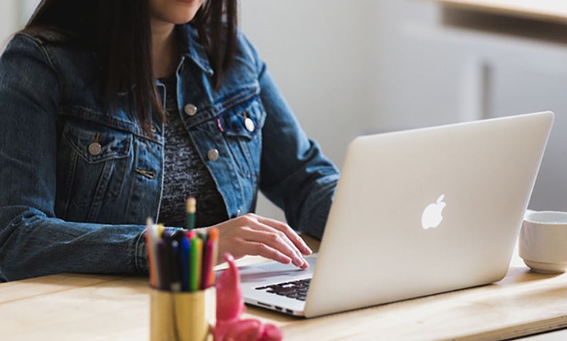 Image of a women using an Apple laptop at a desk 