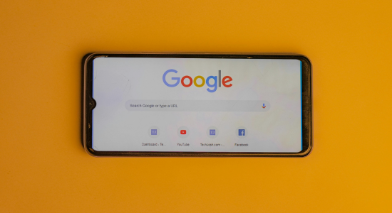 The Google search interface on an iPhone resting on an orange surface.