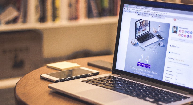 Laptop on a desk, next to an iPhone