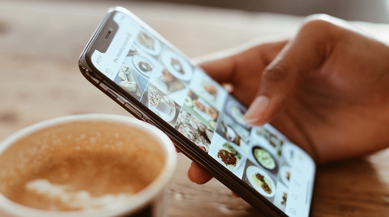 A person looking at foot on Instagram, with a mug of coffee.